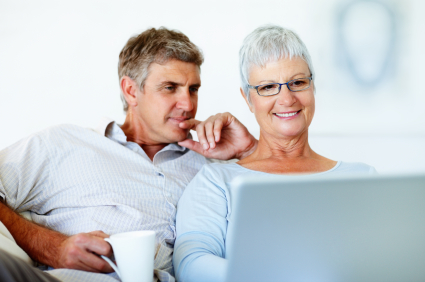 Happy mature woman working on laptop while man looking at it